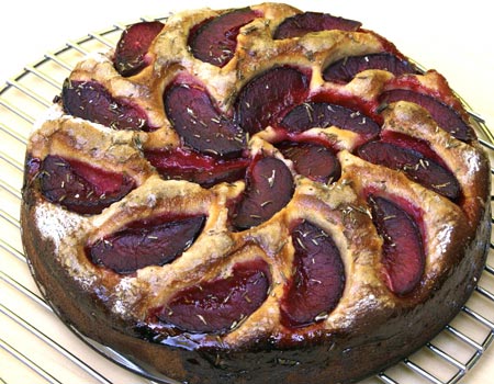 A cake with plums on top of it.