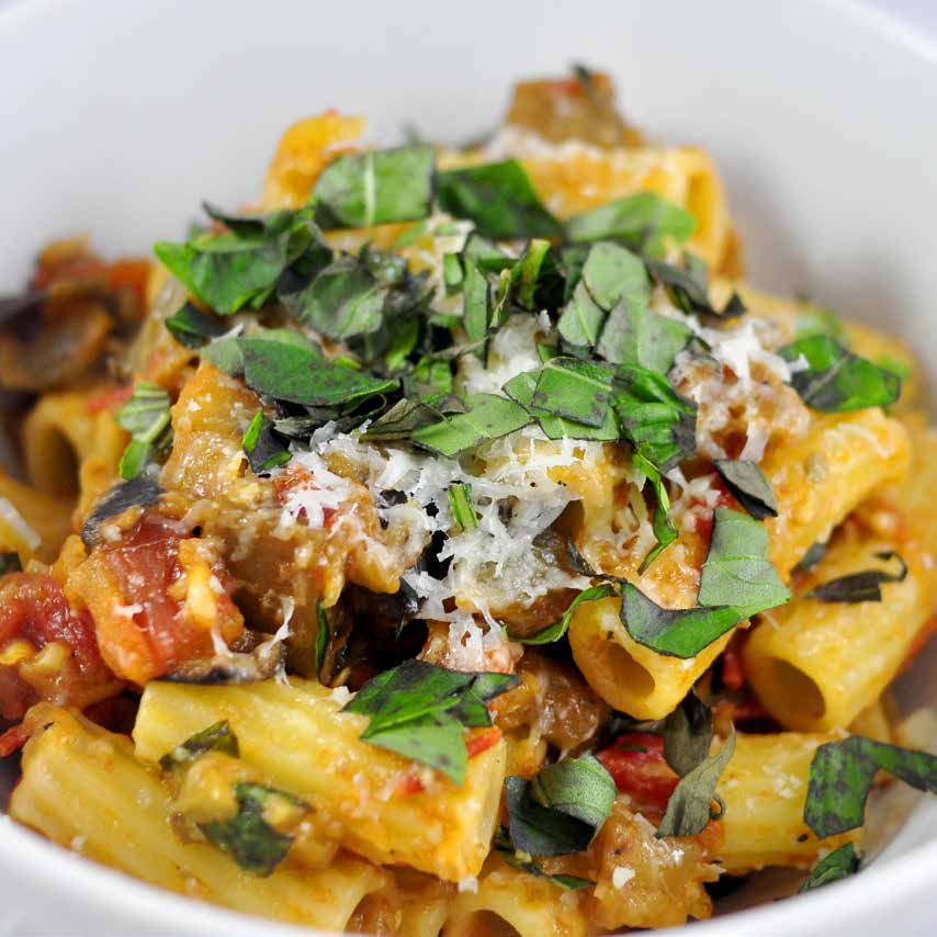 A bowl of pasta with sauce and herbs.