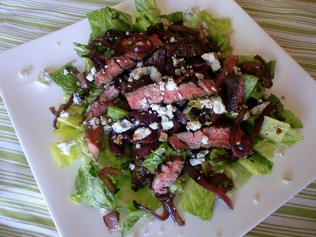 A plate of salad with steak and blue cheese.