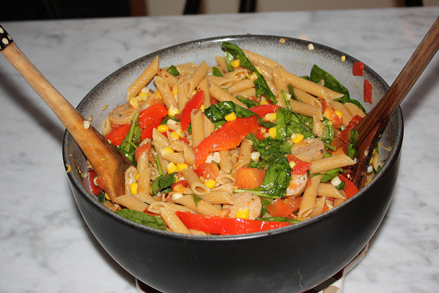 A bowl of pasta with vegetables and sauce.