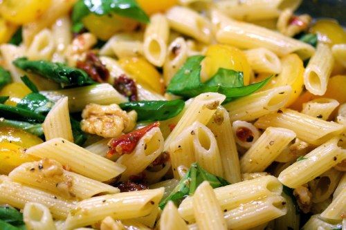 A close up of pasta with spinach and nuts