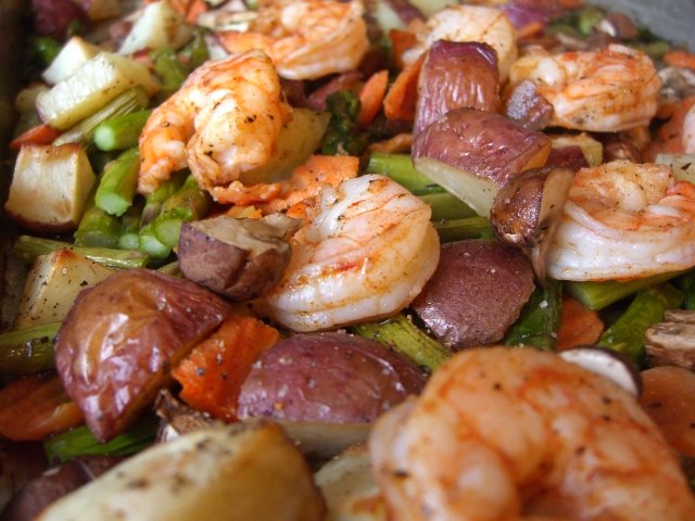 A close up of shrimp and potatoes on the pan