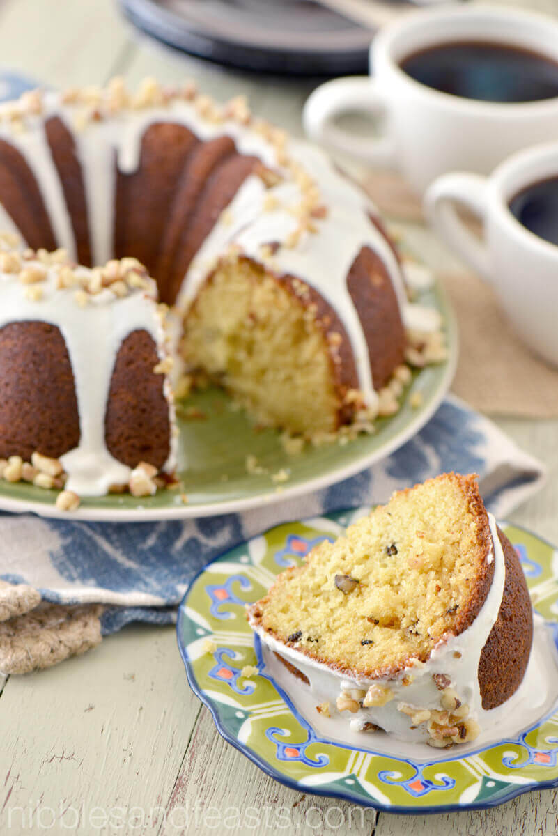 A bundt cake with white frosting and nuts on top.