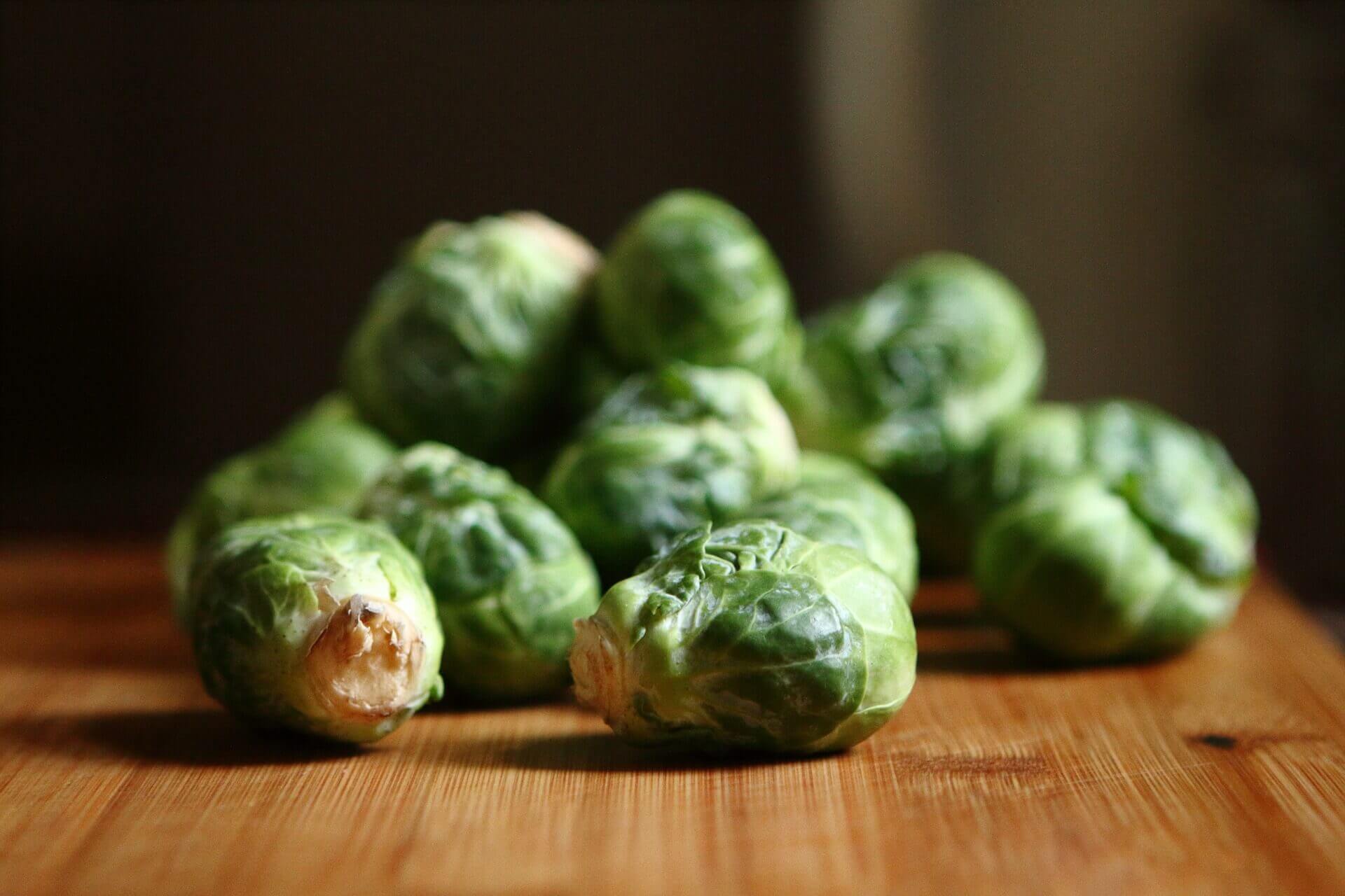 A pile of brussels sprouts sitting on top of a wooden table.