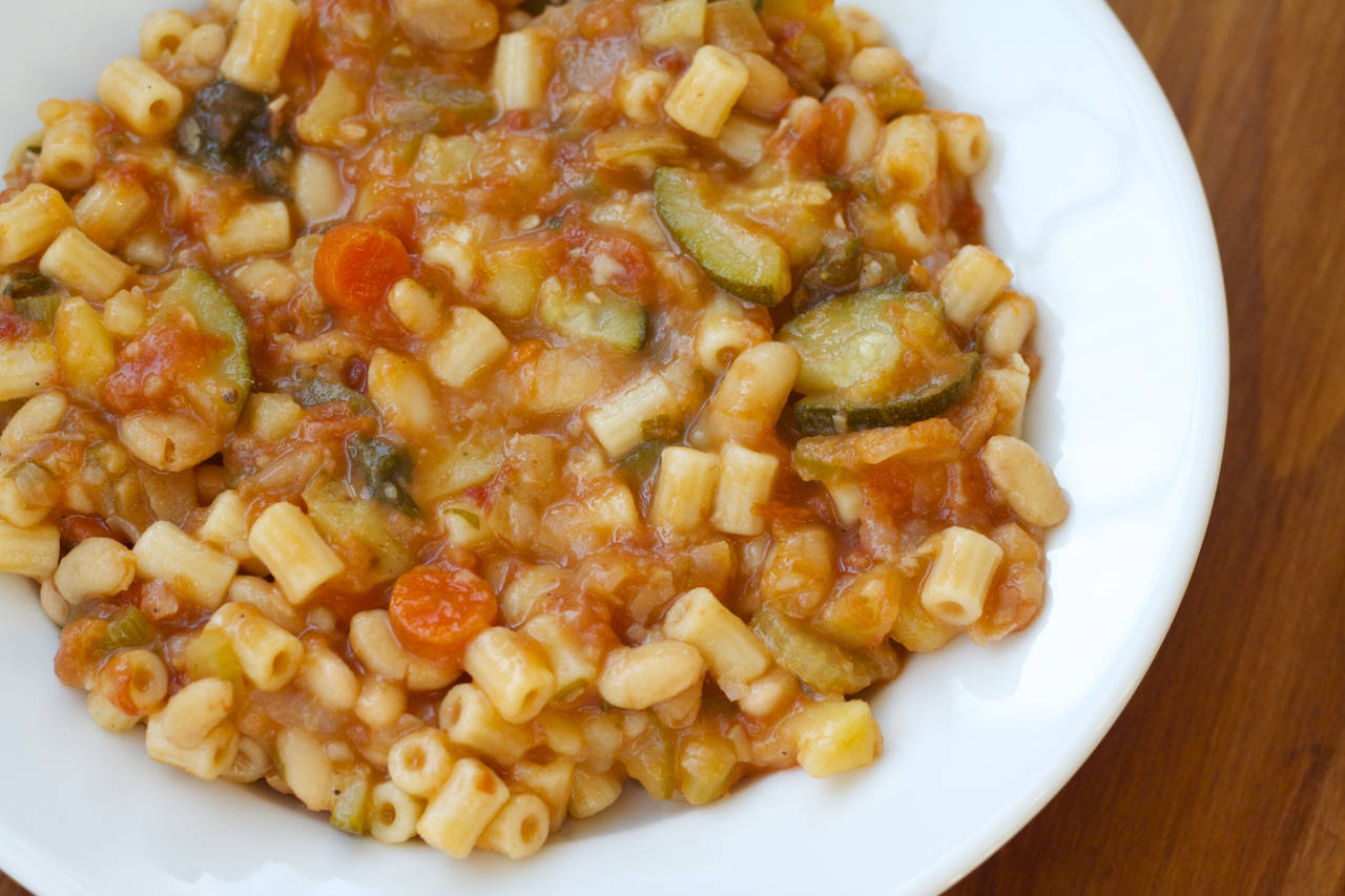 A bowl of pasta with sauce and vegetables.