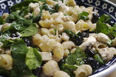 A bowl of pasta with spinach and olives.