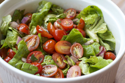 A bowl of salad with tomatoes and lettuce.